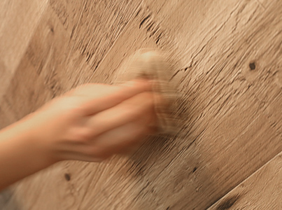 壁紙に残った粘着面の残骸を水で濡らした布でこすっている様子