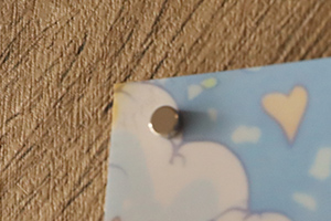 ポスターの左上を丸形超強力マグネットで止めている様子