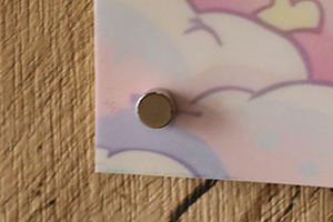 ポスターの左下を丸形超強力マグネットで止めている様子