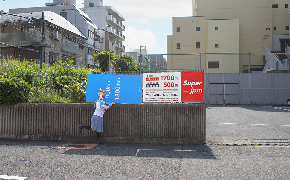 コインパーキングの看板をサブロクサイズの発泡パネルを並べてサイズを比べている様子